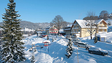 Das Familienhotel Mein Krug im Fichtelgebirge, umgeben von einer winterlichen, verschneiten Umgebung.