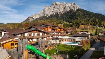 Außenansicht des Familienhotel Tirolerhof in Österreich mit Garten, Spielbereich und Bergpanorama