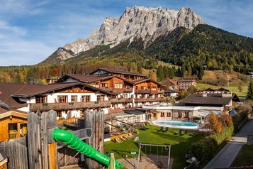 Außenansicht des Familienhotel Tirolerhof in Österreich mit Garten, Spielbereich und Bergpanorama