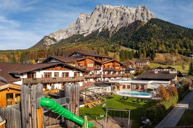 Außenansicht des Familienhotel Tirolerhof in Österreich mit Garten, Spielbereich und Bergpanorama