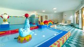 Der Kinderpool im Familienhotel Ramsi in Kärnten ist bunt gestaltet und mit Wasserspielen ausgestattet, bequeme Liegen bieten Platz für entspannte Pausen