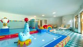 Der Kinderpool im Familienhotel Ramsi in Kärnten ist bunt gestaltet und mit Wasserspielen ausgestattet, bequeme Liegen bieten Platz für entspannte Pausen
