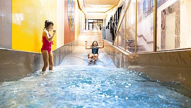 Zwei Mädchen rutschen die Wasserrutsche im Familienhotel Sonnenpark hinunter.