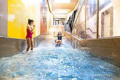 Zwei Mädchen rutschen die Wasserrutsche im Familienhotel Sonnenpark hinunter.