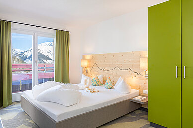 Elternschlafbereich mit einem Balkon und einer Aussicht auf die Berge im Familienhotel Kaiserhof an der Zugspitze.