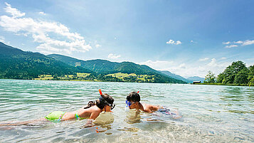 Zwei Kinder schnorcheln im See im Familienurlaub in Kärnten.