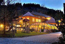 Das Kinderhotel Bruckwirt in Oberösterreich von außen bei Nacht mit schöner Beleuchtung.