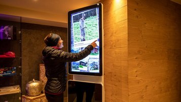 Gast bedient einen interaktiven Informationsscreen im Lobbybereich des Familienhotels Galtenberg