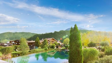 Außenansicht des Familienhotels Landgut Furtherwirt mit blumengeschmückten Balkonen und traditioneller Holzfassade.