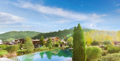 Außenansicht des Familienhotels Landgut Furtherwirt mit blumengeschmückten Balkonen und traditioneller Holzfassade.