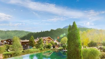 Außenansicht des Familienhotels Landgut Furtherwirt mit blumengeschmückten Balkonen und traditioneller Holzfassade.