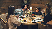 Die ganze Familie sitzt entspannt zum Abendessen im Familienhotel Post Family Resort im Salzburger Land.