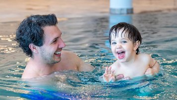 Vater und Sohn planschen fröhlich im Pool des Familienhotels Petschnighof