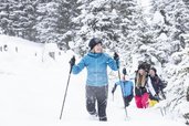 Familie beim Schneeschuhwandern nahe dem Hotel Sonngastein im Salzburger Land durch verschneite Winterlandschaft.