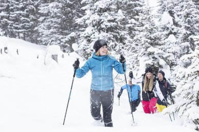 Familie beim Schneeschuhwandern nahe dem Hotel Sonngastein im Salzburger Land durch verschneite Winterlandschaft.