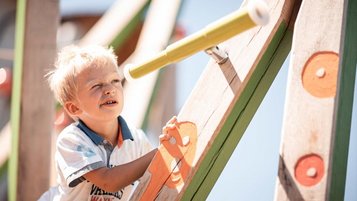 Ein Kind auf dem Kinderspielplatz im Family Home Alpenhof in Südtirol.