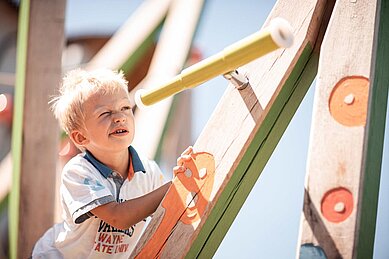 Ein Kind auf dem Kinderspielplatz im Family Home Alpenhof in Südtirol.