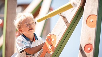 Ein Kind auf dem Kinderspielplatz im Family Home Alpenhof in Südtirol.