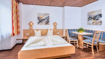 Familienzimmer mit einem Doppelbett und einem Wohnzimmer im Familienhotel Kinderhotel Sailer in Pitztal.