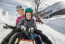 Kinder beim Rodeln am Familienhotel Kinderhotel Stefan in Tirol.