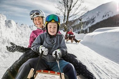 Kinder beim Rodeln am Familienhotel Kinderhotel Stefan in Tirol.