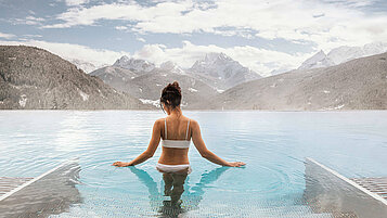 Eine Frau beim Wellness im Pool. Der Teenager genießt die Aussicht in Südtirol.