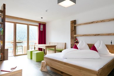 Familienzimmer mit Sitzecke und einem Balkon im Familienhotel Almfamilyhotel Scherer in Tirol.