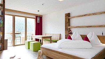 Familienzimmer mit Sitzecke und einem Balkon im Familienhotel Almfamilyhotel Scherer in Tirol.