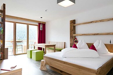 Familienzimmer mit Sitzecke und einem Balkon im Familienhotel Almfamilyhotel Scherer in Tirol.
