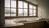 Badewanne mit großen Fenstern im Badezimmer vom Familienhotel Hotel Tirolerhof an der Zugspitze.