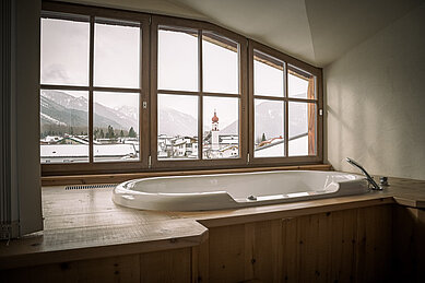 Badewanne mit großen Fenstern im Badezimmer vom Familienhotel Hotel Tirolerhof an der Zugspitze.