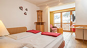 Ein Doppelzimmer mit Wohnbereich und Balkon im Familienhotel Kirchheimerhof in Kärnten.