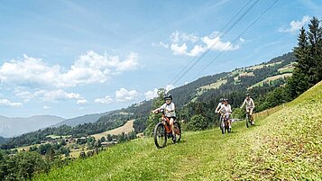 Eine Familie ist auf den Bergen mit den Leihrädern Biken nahe des Familienhotels Das Hopfgarten in Tirol.