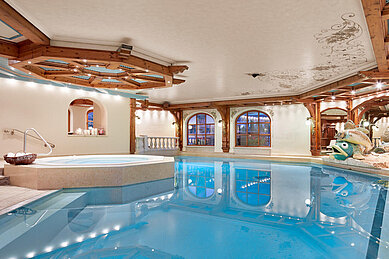 Schönes Indoor Schwimmbad mit großen Fischskulpturen und einem Whirlpool im Familienhotel Hotel Tirolerhof an der Zugspitze.