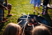 Familien rösten Stockbrot am Lagerfeuer im Familien Resort Petschnighof in Kärnten.