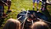 Familien rösten Stockbrot am Lagerfeuer im Familien Resort Petschnighof in Kärnten.