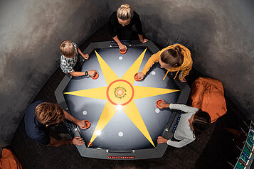 Familie spielt gemeinsam Air Hockey im Family Home Alpenhof.