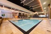 Das Indoor-Schwimmbad im Wellness- & Familienhotel Egger in Saalbach Hinterglemm ist gemütlich eingerichtet mit Pflanzen und Liegen zum Entspannen.
