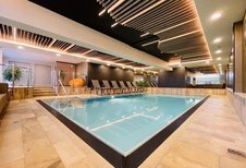 Das Indoor-Schwimmbad im Wellness- & Familienhotel Egger in Saalbach Hinterglemm ist gemütlich eingerichtet mit Pflanzen und Liegen zum Entspannen.