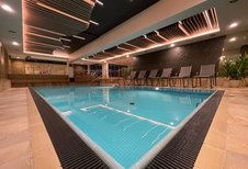 Das Indoor-Schwimmbad im Wellness- & Familienhotel Egger in Saalbach Hinterglemm ist gemütlich eingerichtet mit Pflanzen und Liegen zum Entspannen.