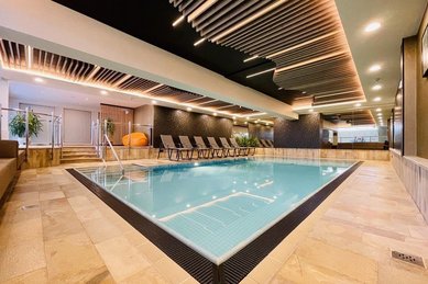 Das Indoor-Schwimmbad im Wellness- & Familienhotel Egger in Saalbach Hinterglemm ist gemütlich eingerichtet mit Pflanzen und Liegen zum Entspannen.