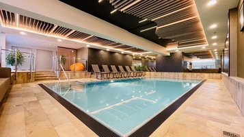 Das Indoor-Schwimmbad im Wellness- & Familienhotel Egger in Saalbach Hinterglemm ist gemütlich eingerichtet mit Pflanzen und Liegen zum Entspannen.