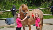 Zwei Mädchen striegeln ein Pony im Familienhotel Familien Resort Petschnighof in Kärnten.