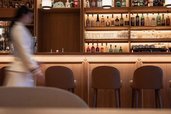 Innenansicht einer Bar mit beleuchteten Regalen und Barhockern im Familienhotel Bella Vista in Suedtirol.