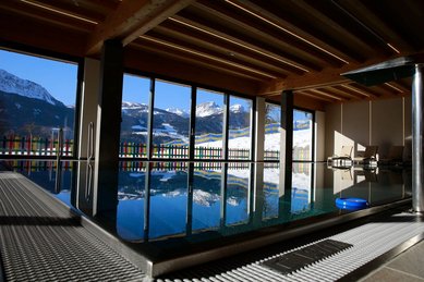 Das Familienhotel Ramsi in Kärnten bietet einen lichtdurchfluteten Indoor Pool mit Panoramablick auf die verschneite Berglandschaft
