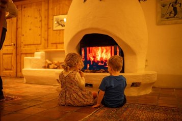 Kinder sitzen gemütlich am Kamin im Familienhotel Tirolerhof in Österreich