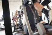 Eine Frau trainiert auf einem Fahrrad-Ergometer, im Vordergrund ein Mann auf einem Crosstrainer im Allgäuer Berghof.