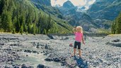Ein Kind spielt nahe dem Familienhotel Bella Vista in Südtirol in einem Bachbett mit Blick auf die Berge.