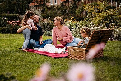 Familie beim Picknick in der Natur auf dem Außengelände des Familienhotels Landhaus Averbeck in der Lüneburger Heide.