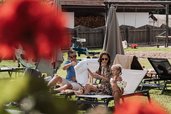 Eine Familie genießt im Familienhotel Tirolerhof entspannte Stunden am Pool mit Blick auf den Spielplatz und die Tiroler Berge